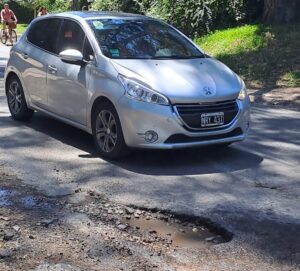 Bache profundo con agua en Avenida Arana 419 de Villa Elisa mientras un auto intenta esquivarlo