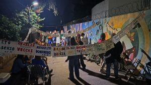 Vecinos y vecinas participan de una jornada de bordado colectivo en el Paseo de la Memoria de Villa Elisa, con pañuelos colgados que recuerdan a personas detenidas desaparecidas.